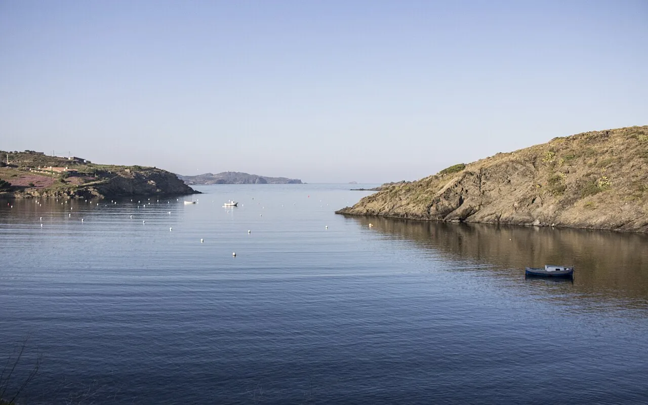 Die ruhige Bucht von Portlligat mit kleinen Booten vor Anker und den niedrigen Hügeln des Cap de Creus