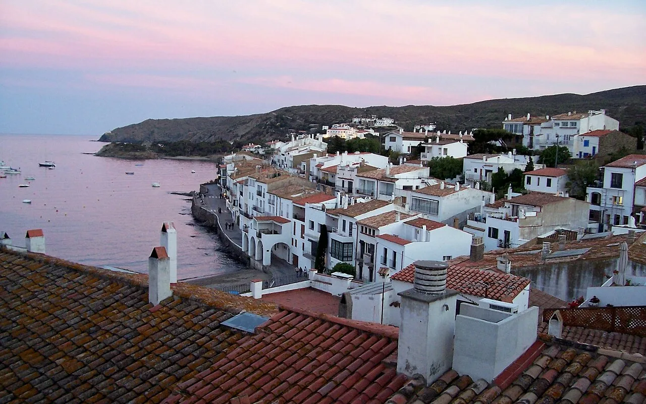 Weiß getünchte Häuser und Terrakottadächer von Cadaqués über dem Meer in der Abenddämmerung