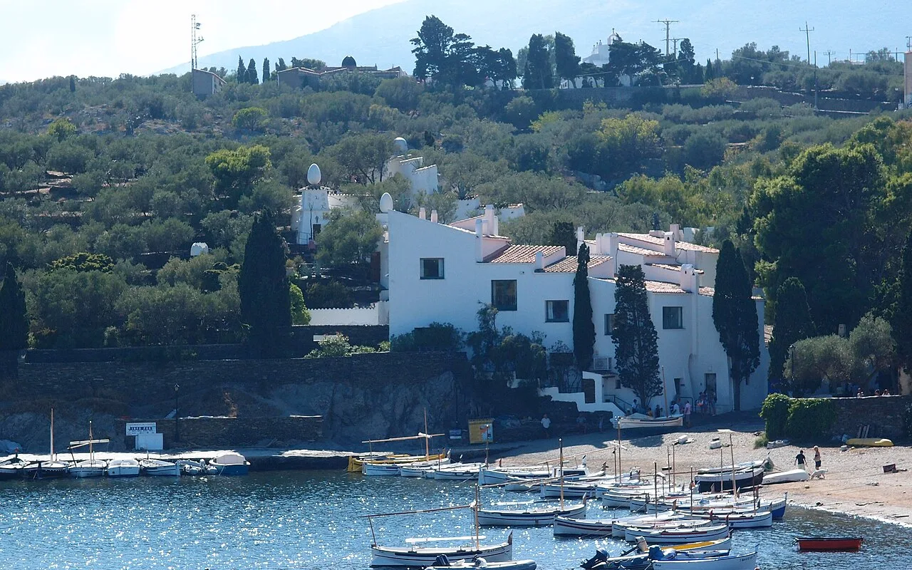 Dalís Haus in Portlligat hinter einem Hafen voller kleiner weißer Fischerboote