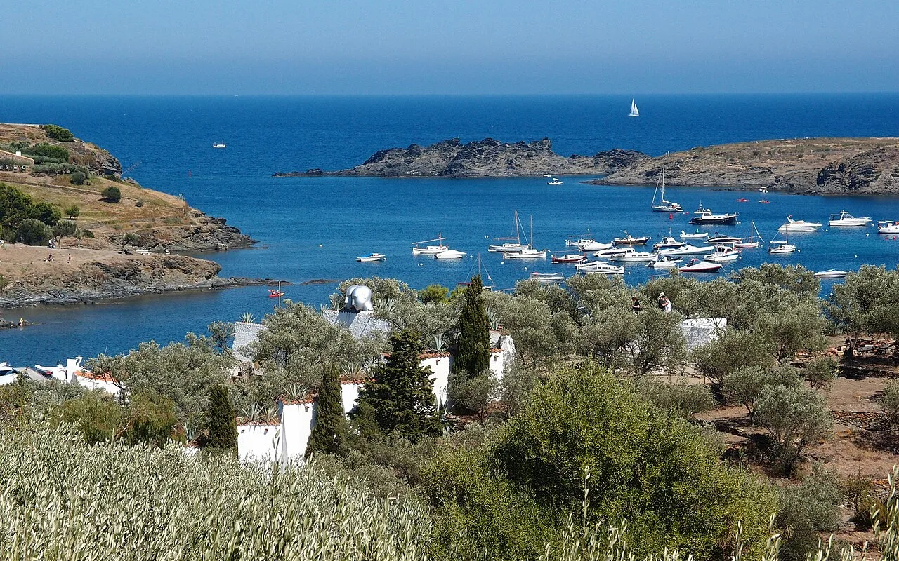 Oliventerrassen und Zypressen, die sich bis zur Bucht von Portlligat mit Booten auf dem Wasser hinunterziehen