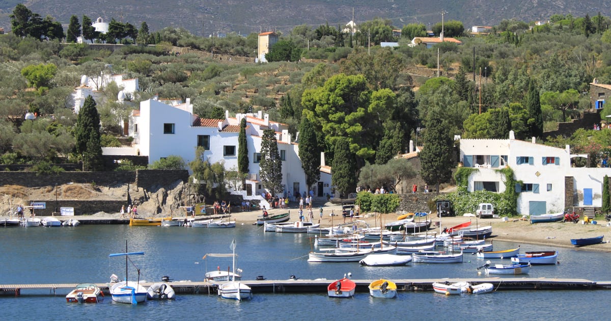 Ασπρισμένο σπίτι του Salvador Dalí πάνω από τον κόλπο Portlligat, με ψαρόβαρκες δεμένες μπροστά και τους λόφους Cap de Creus πίσω